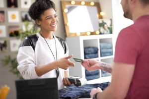 happy sales assistant in clothes store receives payment